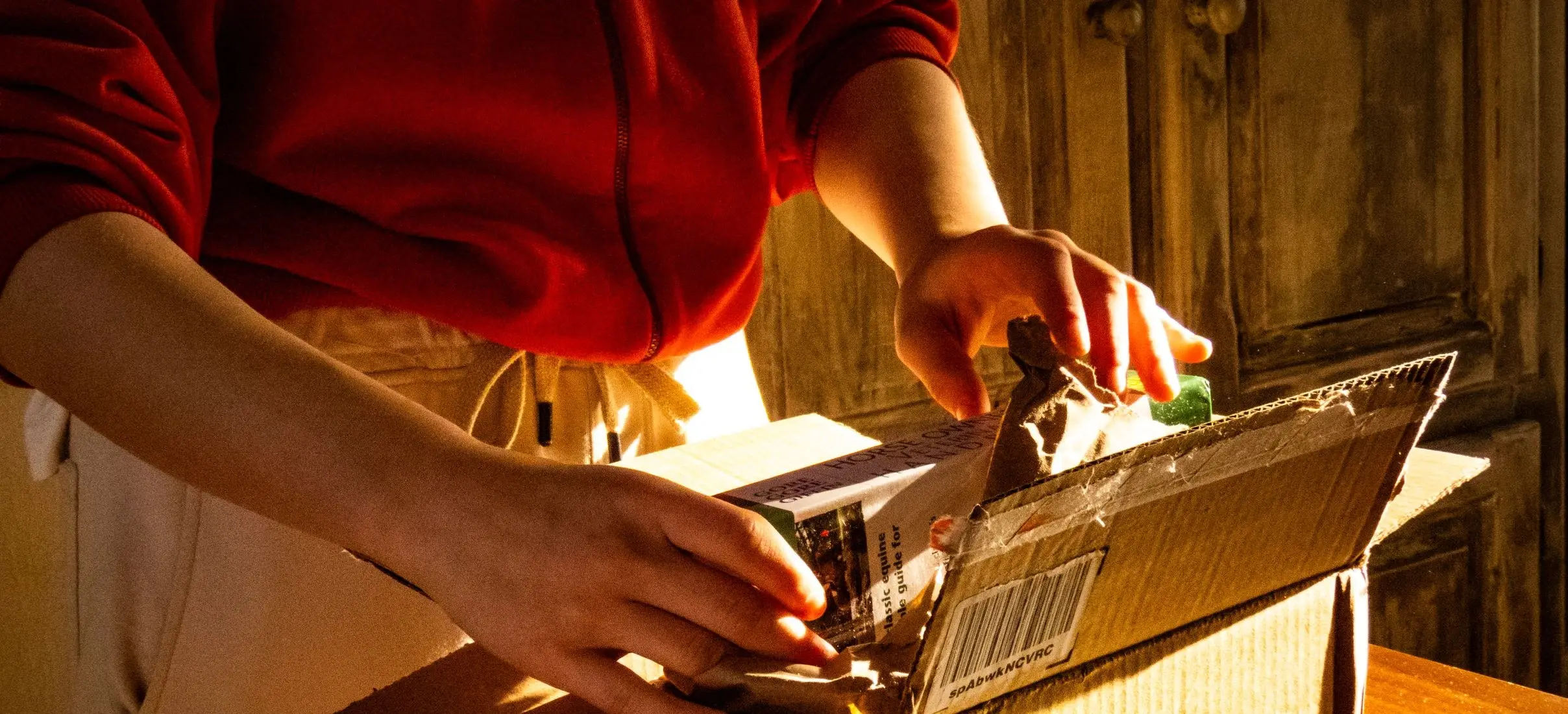 Opening a just-delivered parcel on a desk in warm light